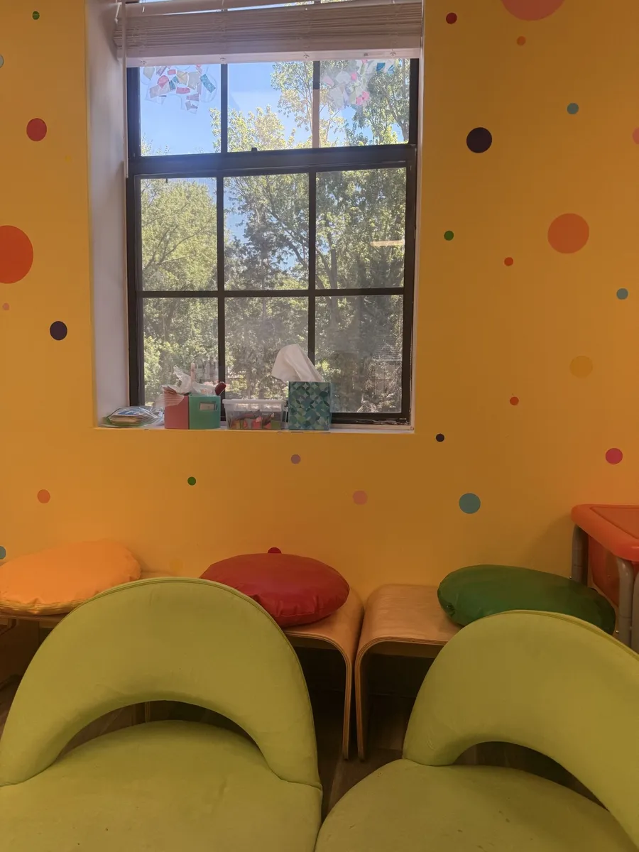 Yellow polka-dot room with soft green chairs and floor cushions under a window