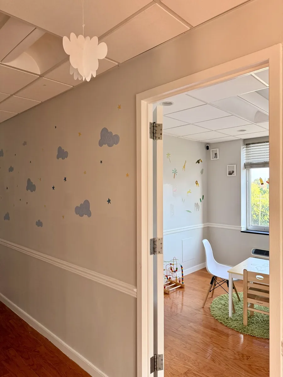Hallway with a cloud mural leading into a sunny therapy room
