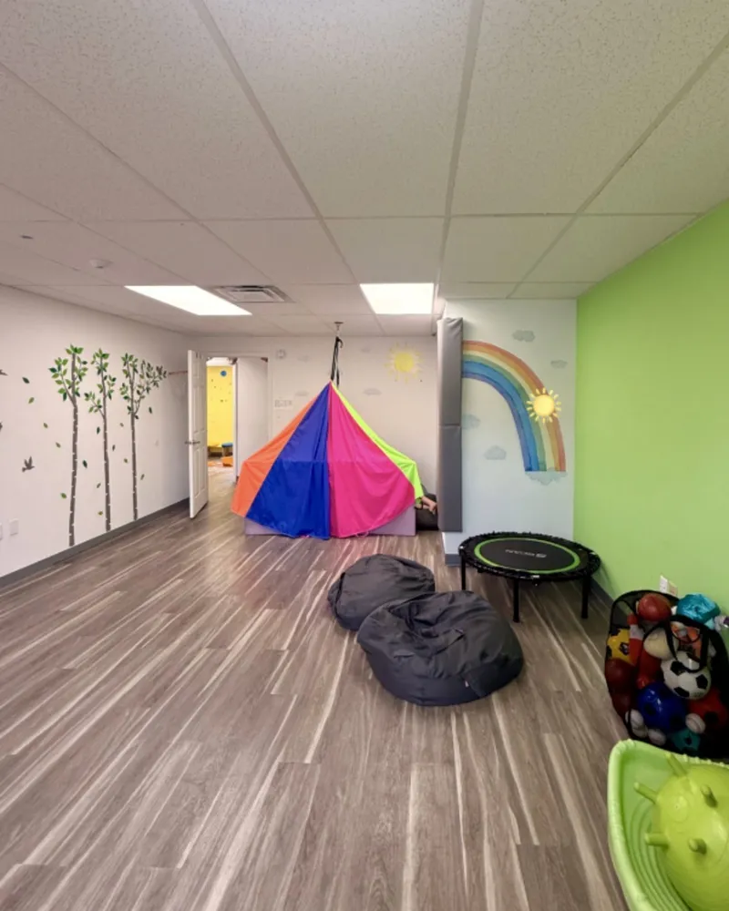 Sensory gym with a rainbow mural and colorful play tent