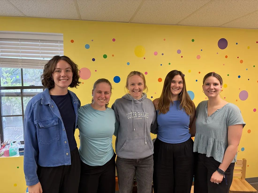 Five Imagine That therapists smiling in front of a yellow polka-dot wall